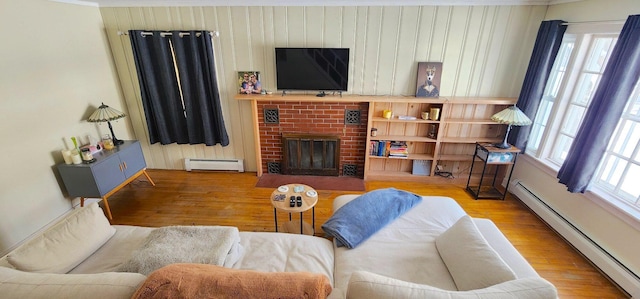 living room featuring a fireplace, a baseboard radiator, wood finished floors, and a healthy amount of sunlight