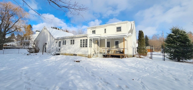 snow covered rear of property with fence