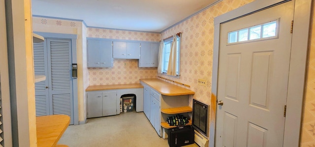 kitchen featuring light countertops, open shelves, blue cabinetry, and wallpapered walls