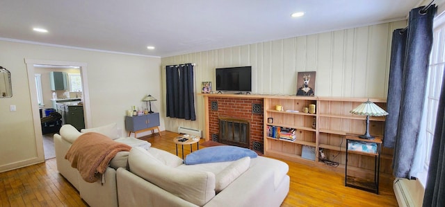 living area with a brick fireplace, wood-type flooring, baseboard heating, and recessed lighting