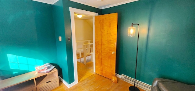 bathroom featuring ornamental molding, baseboards, baseboard heating, and wood finished floors