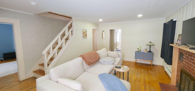 living area featuring ornamental molding, stairs, light wood-style floors, a baseboard heating unit, and recessed lighting