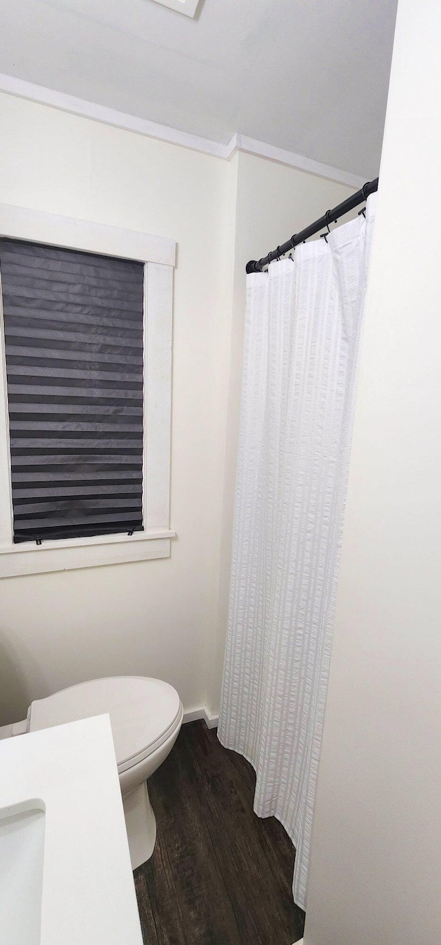 bathroom with curtained shower, wood finished floors, toilet, and baseboards