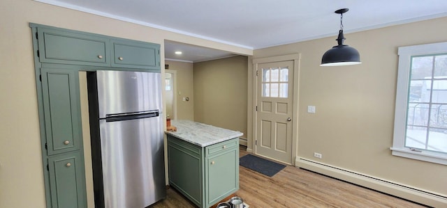 kitchen featuring a baseboard radiator, wood finished floors, hanging light fixtures, freestanding refrigerator, and green cabinetry