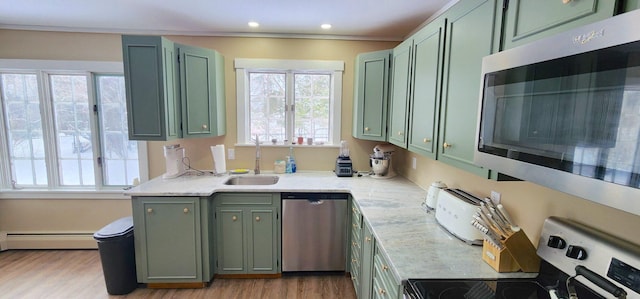 kitchen featuring green cabinets, appliances with stainless steel finishes, baseboard heating, and a sink