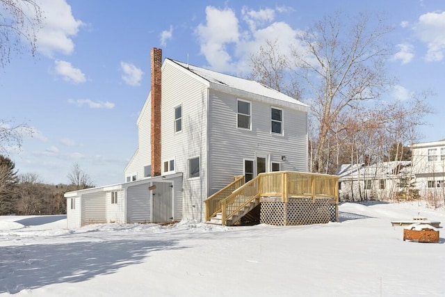 snow covered back of property featuring stairs, a chimney, and a wooden deck