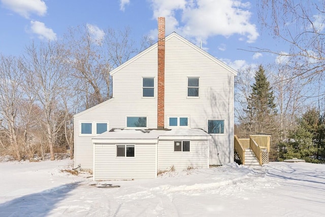 snow covered property with stairway and a chimney