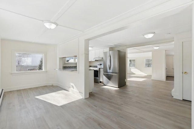 empty room with light wood-type flooring, a baseboard heating unit, and baseboards