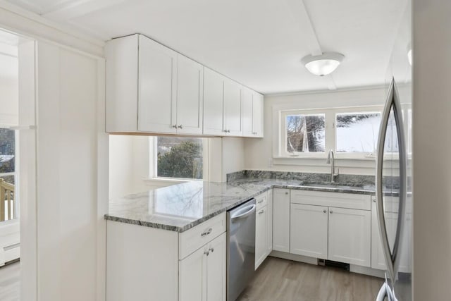 kitchen featuring stainless steel appliances, a sink, a wealth of natural light, and white cabinets