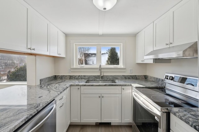 kitchen with light stone counters, under cabinet range hood, a sink, white cabinetry, and appliances with stainless steel finishes