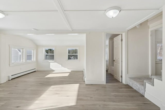 empty room with stairs, light wood finished floors, vaulted ceiling, and a baseboard radiator