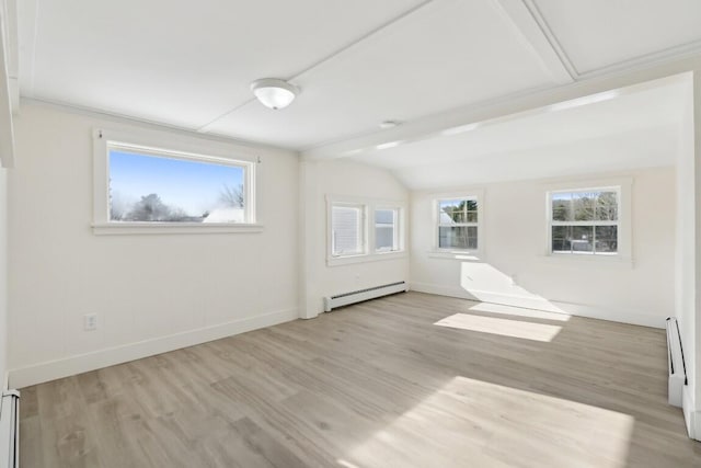 spare room with baseboards, vaulted ceiling, baseboard heating, and wood finished floors