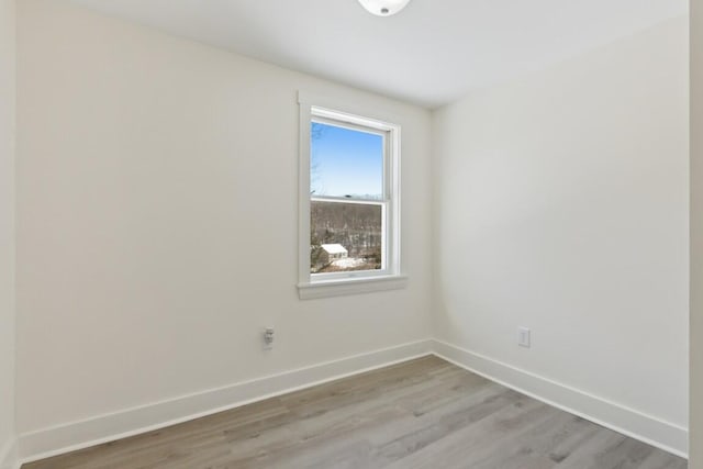 spare room featuring light wood-type flooring and baseboards