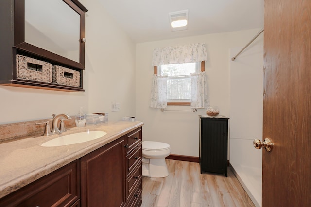 bathroom featuring visible vents, toilet, vanity, wood finished floors, and baseboards