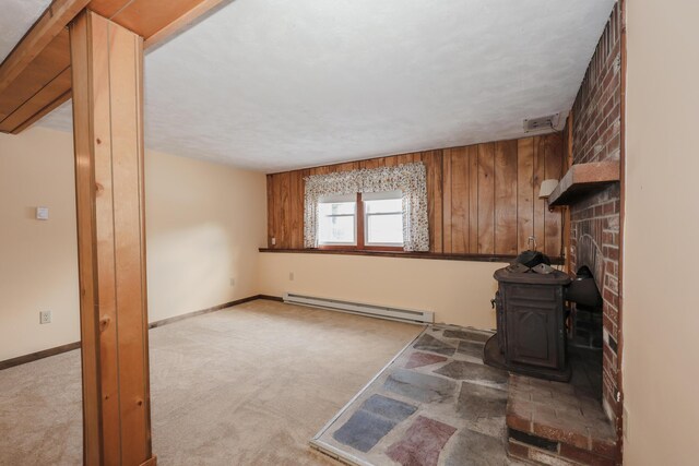 living area with baseboards, a baseboard radiator, a wood stove, and light colored carpet