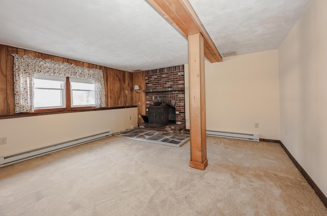 unfurnished living room with baseboards, light carpet, a wood stove, and baseboard heating