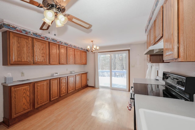 kitchen featuring brown cabinets, under cabinet range hood, and light countertops