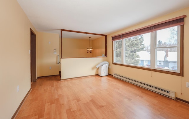 empty room featuring a wealth of natural light, a baseboard radiator, baseboards, and wood finished floors