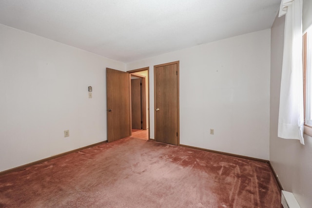 carpeted empty room with a baseboard heating unit and baseboards