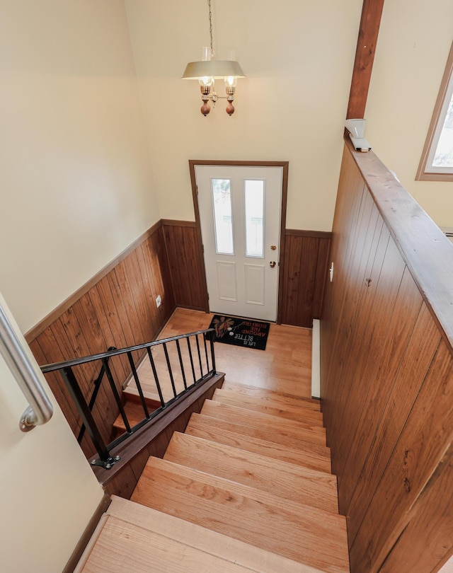 stairway featuring wainscoting, wood finished floors, and wooden walls