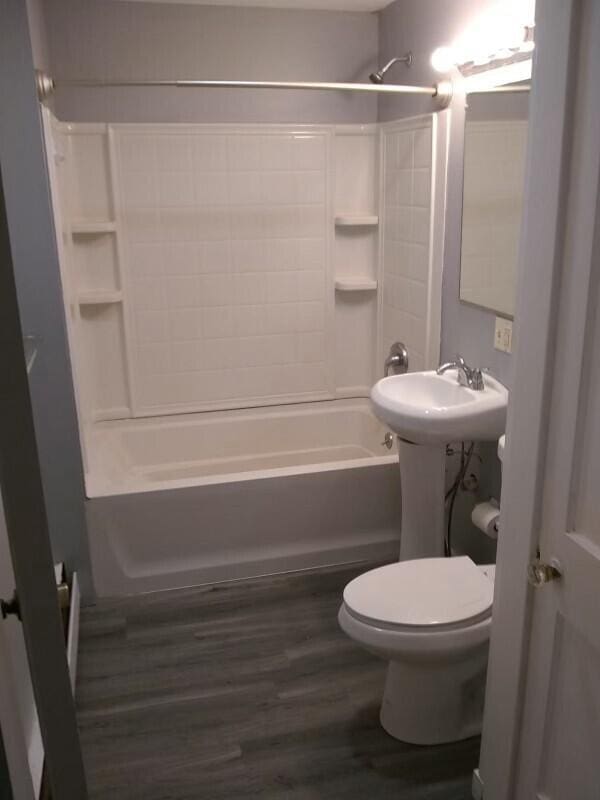 bathroom featuring hardwood / wood-style flooring, bathtub / shower combination, and toilet