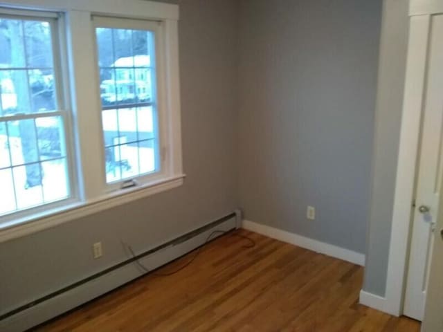 unfurnished room with a baseboard radiator and light wood-type flooring