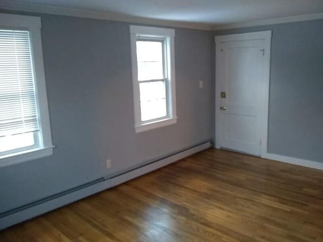 empty room with a baseboard radiator, plenty of natural light, and crown molding