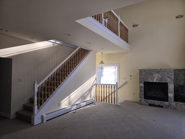 staircase with a baseboard heating unit, a fireplace, carpet floors, and a high ceiling