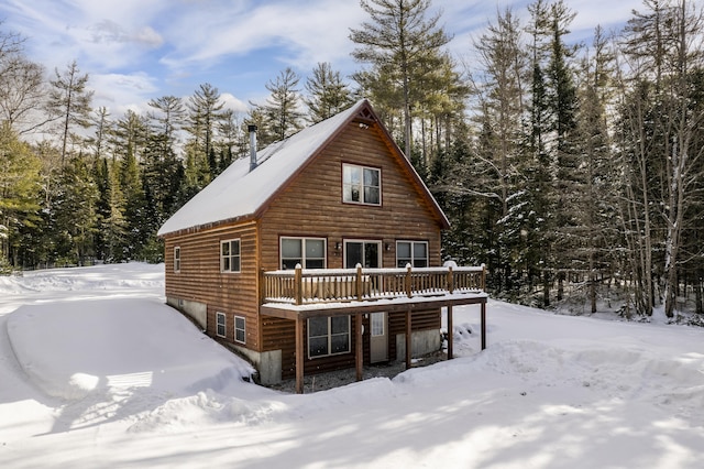 snow covered back of property featuring a deck