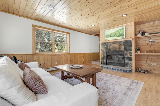 living room featuring a stone fireplace, wood walls, wooden ceiling, a baseboard radiator, and hardwood / wood-style flooring