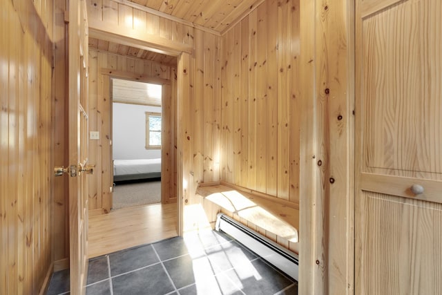 interior space featuring dark tile patterned flooring, wood ceiling, wooden walls, and baseboard heating