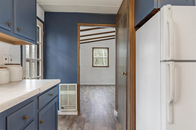 kitchen featuring blue cabinets, dark hardwood / wood-style flooring, lofted ceiling with beams, and white fridge