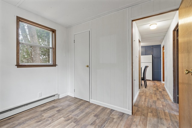 unfurnished bedroom with hardwood / wood-style flooring, a baseboard radiator, and white refrigerator