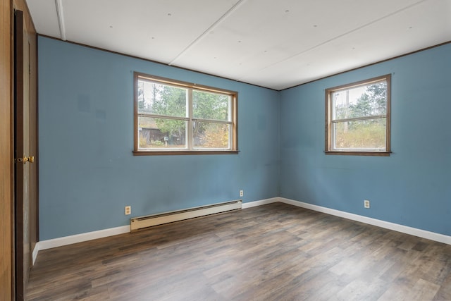 empty room featuring a baseboard heating unit and dark wood-type flooring