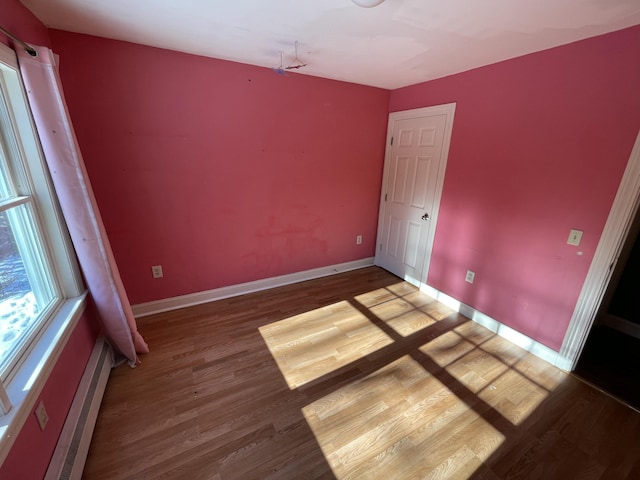 empty room featuring wood-type flooring and a baseboard radiator