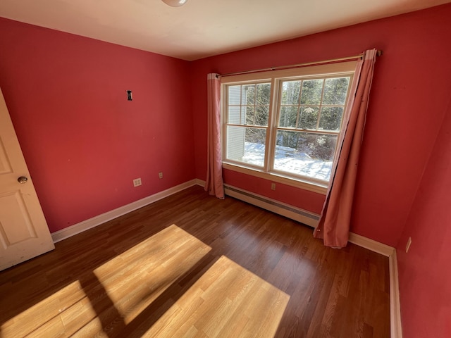 spare room featuring baseboard heating and hardwood / wood-style floors