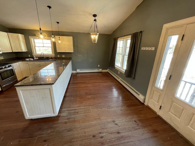 kitchen with dark stone countertops, sink, stainless steel gas range oven, and baseboard heating