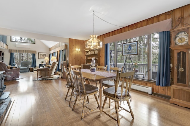 417 Middle Rd, Falmouth, ME 04105 - dining room with a baseboard radiator, vaulted ceiling, wooden walls, light wood-type flooring, and a notable chandelier