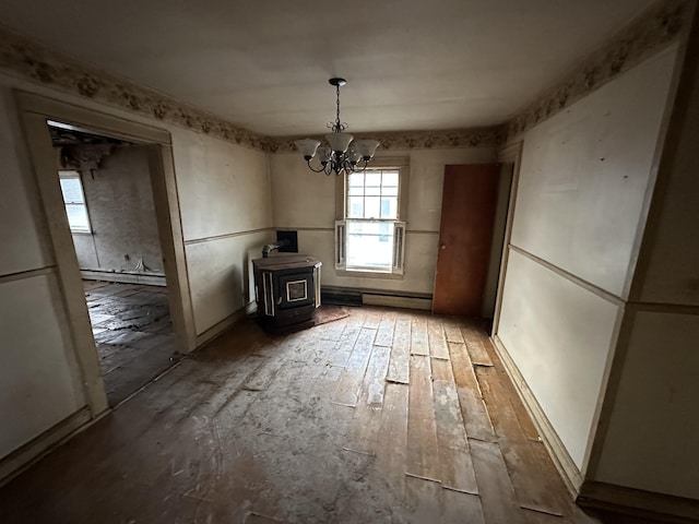 unfurnished dining area featuring a baseboard heating unit, a notable chandelier, wood-type flooring, and a wood stove