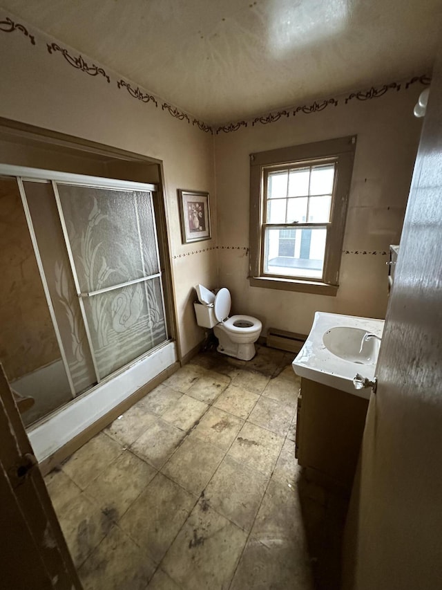 bathroom with a shower with door, vanity, baseboard heating, and toilet