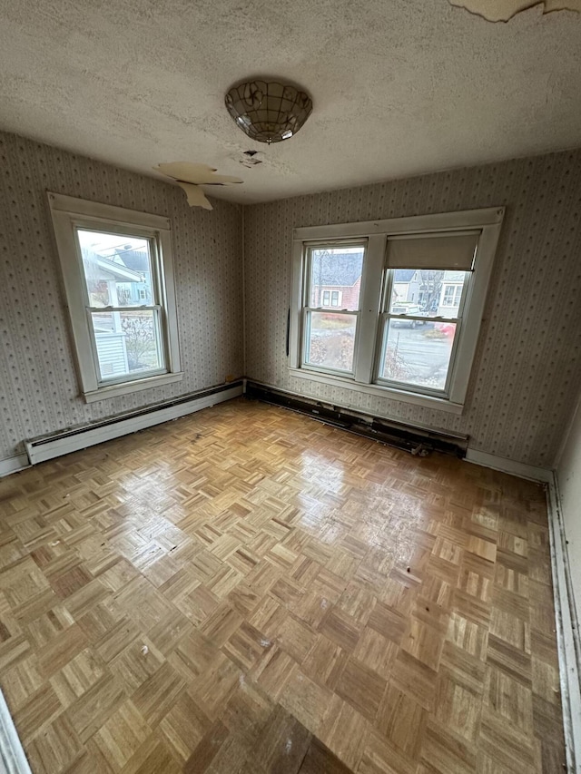 unfurnished room with light parquet flooring, a textured ceiling, and baseboard heating