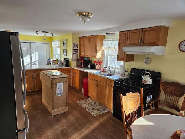 kitchen featuring black range with gas cooktop, sink, a center island, dark hardwood / wood-style floors, and stainless steel fridge