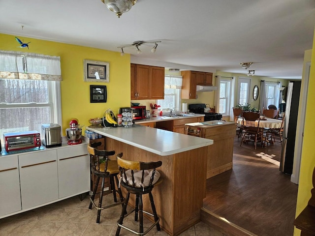 kitchen featuring stove, sink, a breakfast bar, and kitchen peninsula