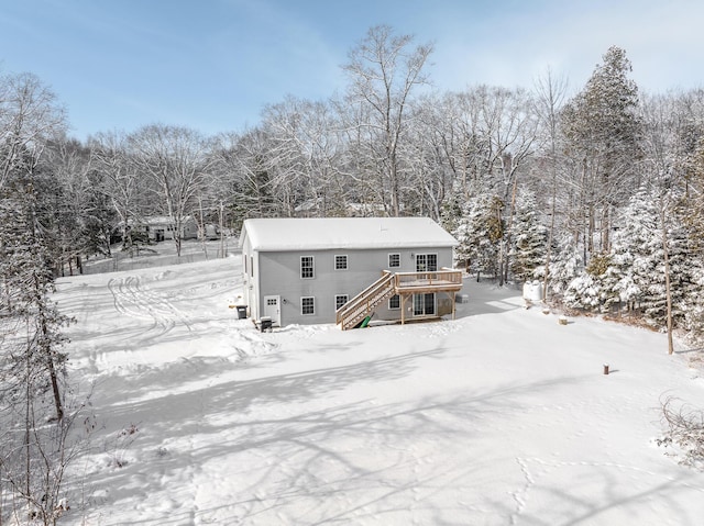 snow covered back of property with a deck