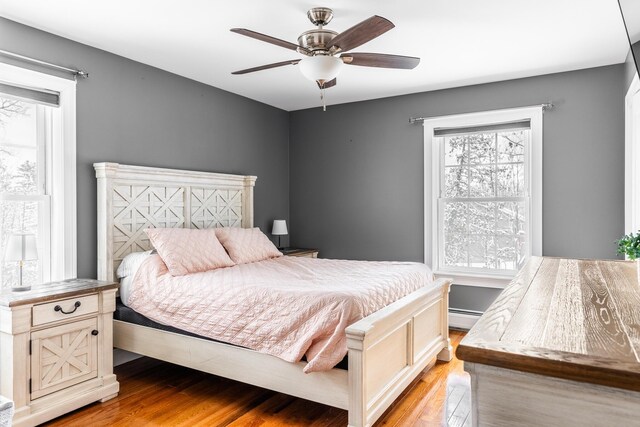 bedroom with light hardwood / wood-style flooring, ceiling fan, and baseboard heating