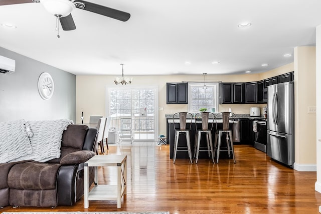 kitchen featuring stainless steel refrigerator, a kitchen bar, hanging light fixtures, a center island, and dark wood-type flooring