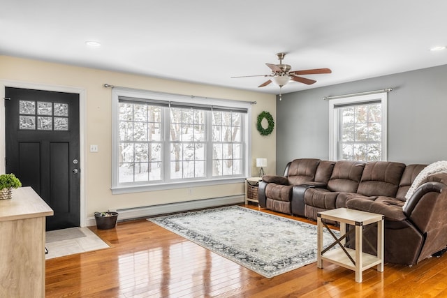 living room with ceiling fan, baseboard heating, and light hardwood / wood-style flooring