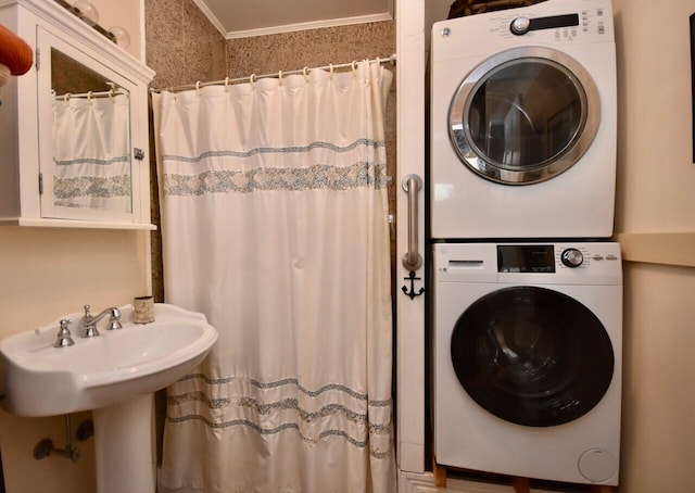 clothes washing area featuring crown molding and stacked washer and clothes dryer