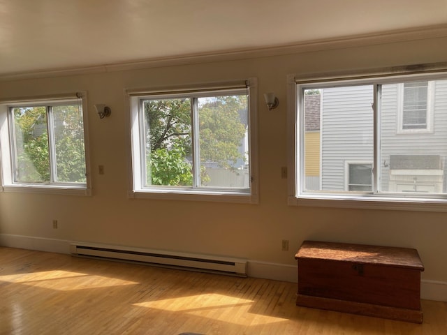 spare room featuring baseboard heating, plenty of natural light, and light wood-type flooring