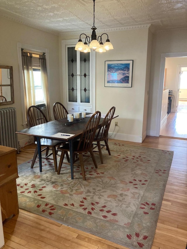 dining area featuring radiator heating unit, a chandelier, and light wood-type flooring